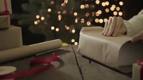 Woman Wrapping Christmas Presents at Night at Home