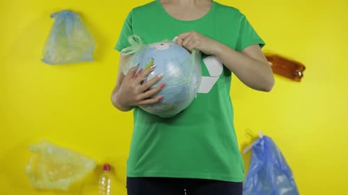 Una mujer irreconocible hace que el globo terrestre esté libre de un paquete de plástico. Salva la ecología. Contaminación natural