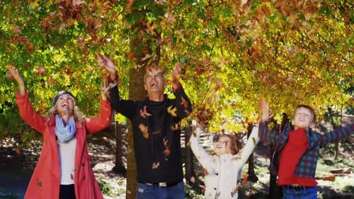 Family Throws Leaves in Autumn Park Setting