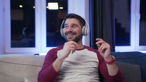 Man Listens to Music with Headphones on Couch