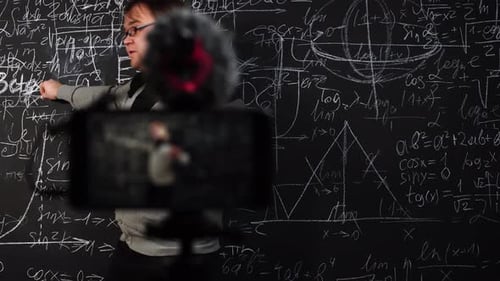 Math Teacher Explains Equations on Chalkboard for Video