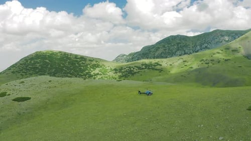 Landcscape Green Fields on the Mountain Hills with Group Tourist People Flying on Helicopter