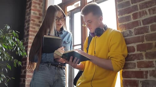 Young Adults Reading Together Indoors by Brick Wall