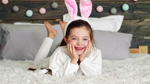 Smiling Girl with Bunny Ears Lying on Bed