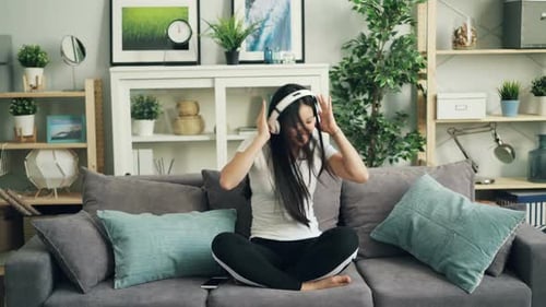 Woman Listening to Music and Dancing on Couch