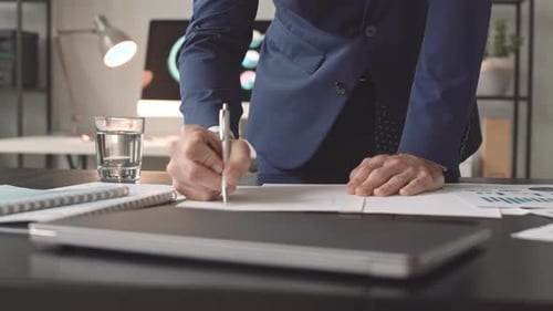 Adult Signs Paperwork in an Office Workplace