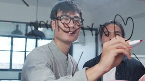 Team Brainstorming Writing on Glass Wall in Office