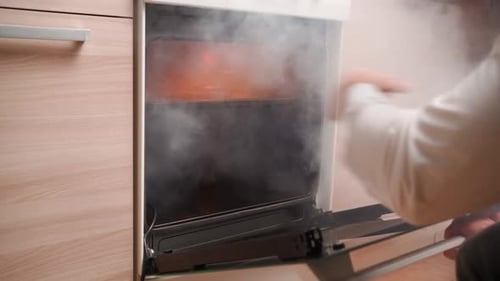 Man Opens an Oven Full Smoke in Kitchen