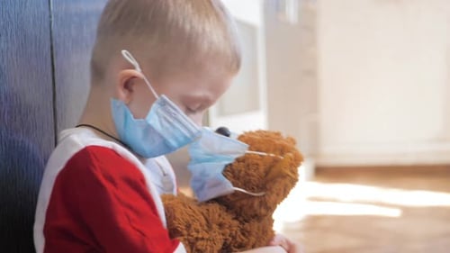 Child with Teddy Bear Wearing Surgical Masks Indoors