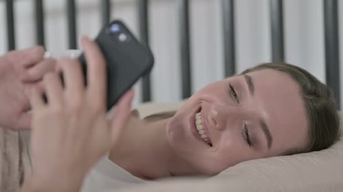 Smiling Woman Using Smartphone Lying in Bed