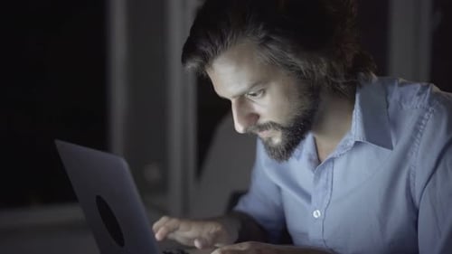 Man Working on Laptop Computer at Night