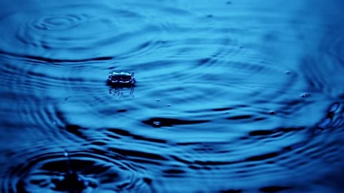 Water Droplets Ripple in Blue Liquid