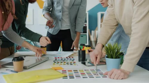 Mittlere Aufnahme von Designern, die während eines kreativen Team-Meetings im Büro auf Farben zeigen