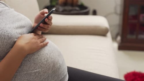 Pregnant Woman Using Phone on Couch