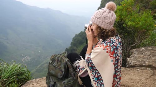 Jeune femme voyageuse avec sac à dos prenant une photo avec appareil photo au sommet de la montagne