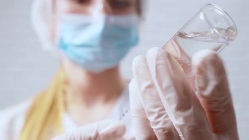 Nurse in Protective Mask Dials Medicine From Coronavirus Into Syringe
