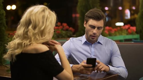 Femme essayant d'attirer l'attention de son petit ami qui travaille activement au téléphone