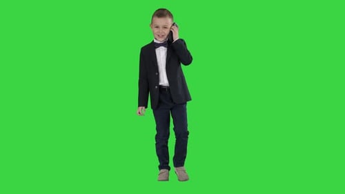 Little Boy in a Costume Making a Phone Call While Walking on a Green Screen, Chroma Key.