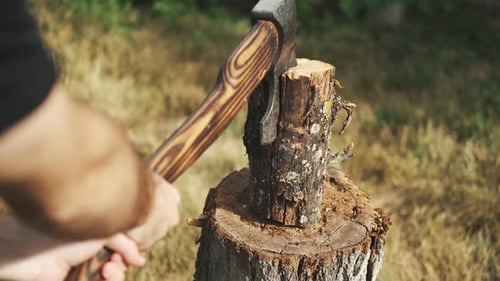 Close-up guy chopping wood with an ax on a log. Spreads the shavings. Rest in a country house