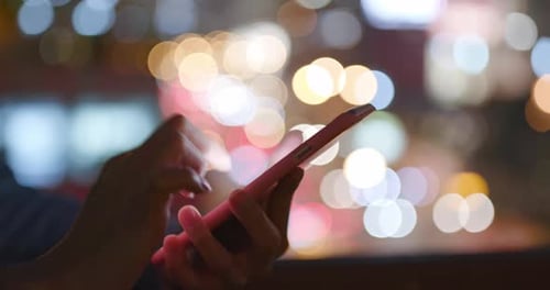 Working on mobile phone over city traffic at night