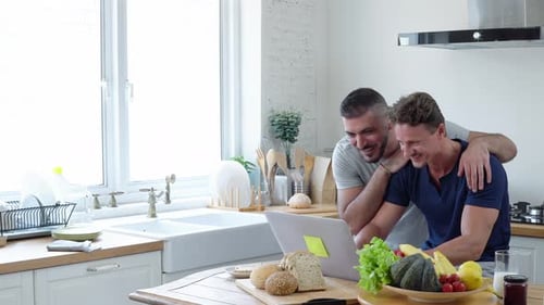 Happy Couple Using Laptop in Bright Kitchen