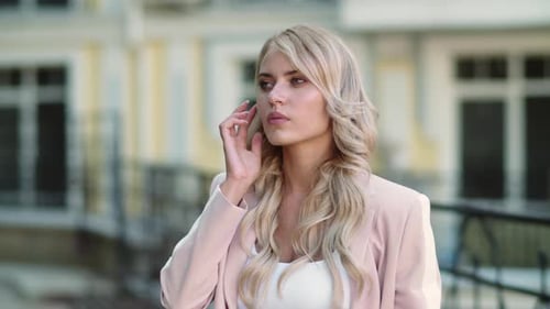 Woman Talking with Wireless Earbud in City