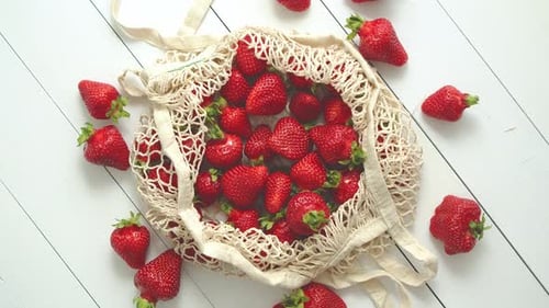Fresas frescas en paquete ecológico sobre fondo de madera blanca. Comida orgánica vegetariana