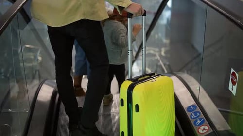 Rare View of Caucasian Family with Yellow Stylish Suitcase Going Down By the Escalator with Their