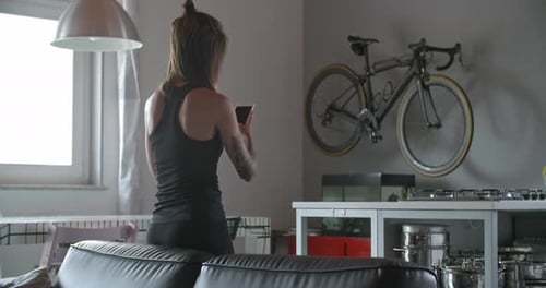 Woman Sits and Looks at Her Cellphone Indoors