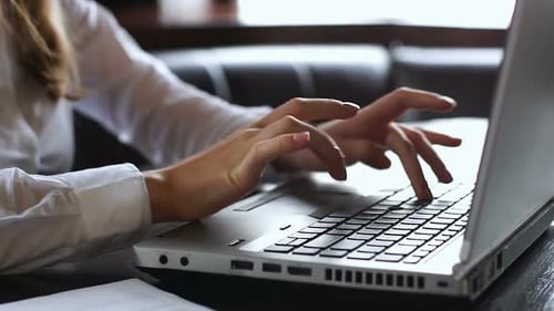 Woman Typing at Silver Laptop on Desk