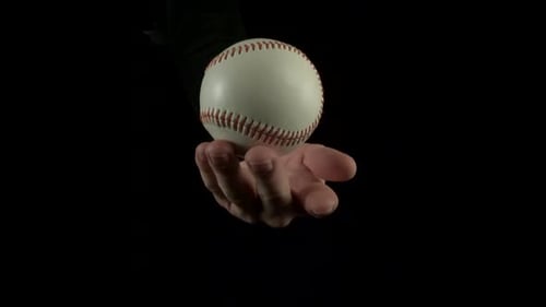Hand Balancing Baseball on Finger on Black Backdrop