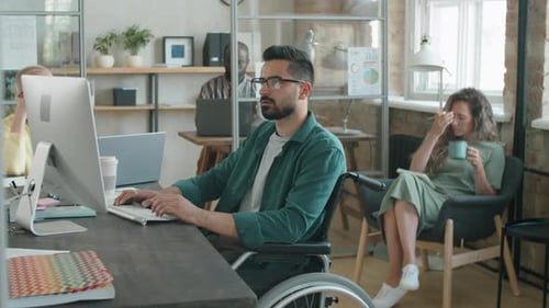 Homme d'affaires du Moyen-Orient assis en fauteuil roulant et travaillant sur un ordinateur