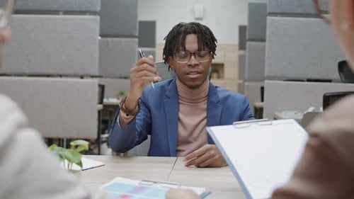 Young Adult Passes Clipboard in Modern Office