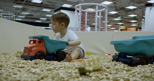 Boy Plays with Toy Trucks in Indoor Play Area