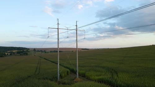 High Voltage Tower with Electric Power Lines Between Green Agricultural Fields