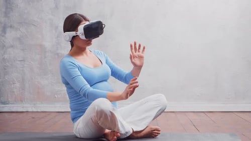 Pregnant Woman Experiencing Virtual Reality Sitting on Yoga Mat