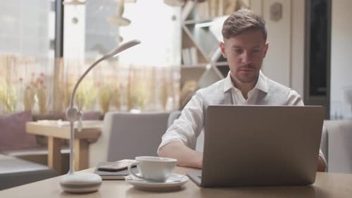Geschäftsmann sitzt und arbeitet in einem Café. Mann benutzt Computer.