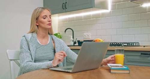 Woman Works on Laptop and Drinks Juice