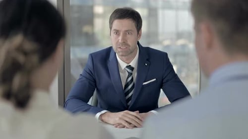 Wütender Geschäftsmann mittleren Alters im Gespräch mit Mitarbeitern bei der Arbeit