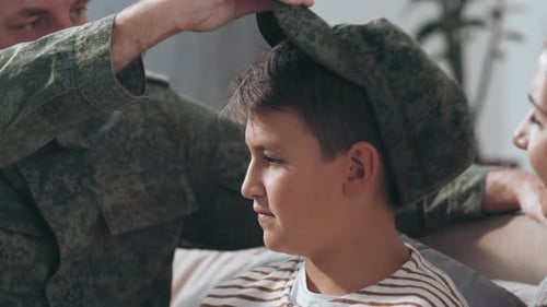 Military Father Puts Cap on Son's Head at Home