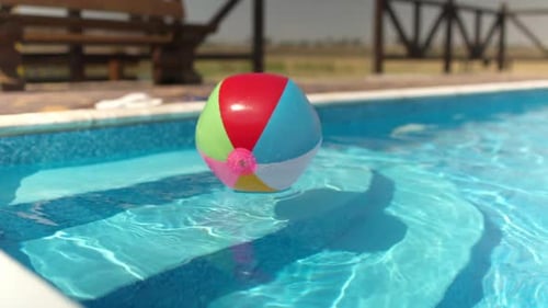 Ein aufblasbarer Ball schwimmt auf einem blauen Pool mit klarem Wasser unter der Sommersonne