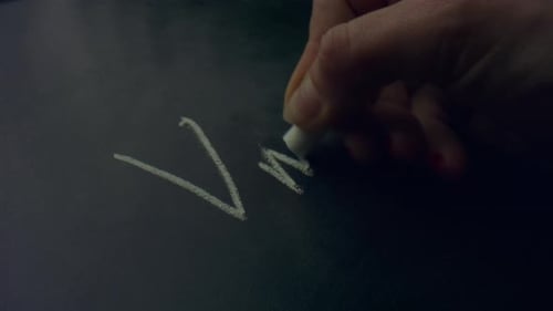Woman Hand Holding Piece of Chalk. Unknown Person Writing Equation on Chalkboard