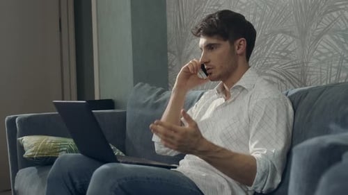 Man Using Laptop and Phone on Couch