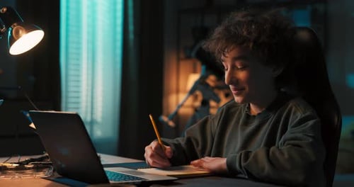 Boy Learning Online with Laptop and Notebook
