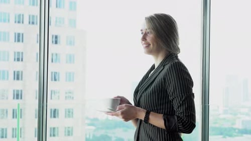 Beautiful young businesswoman confident drinking coffee for leisure after work at window in office.