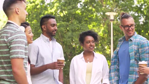 Friends Talking and Holding Coffee in Park