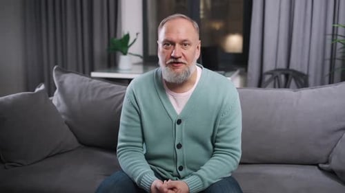 Mature Man Talking On Couch At Home