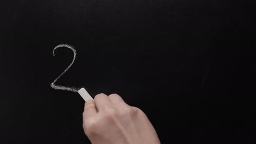 Hand Writes Math Equation on Chalkboard
