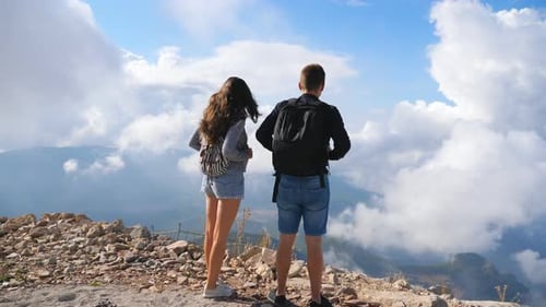 Couple of Hikers with Backpacks Standing on Mountain Edge and Enjoying Landscape. Man and Woman