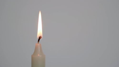 Single White Candle Burning in Still Life